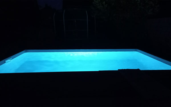 Rechteckpool bei Nacht mit einem Unterwasserscheinwerfer